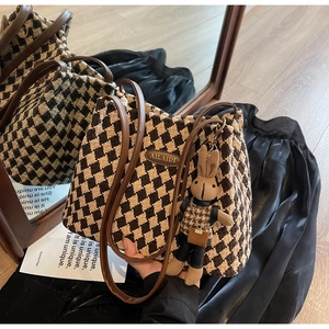 Detail of houndstooth tote bag with brown leather straps and cute rabbit charm accessory