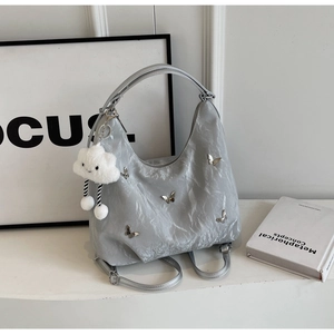 Close-up of grey crinkled hobo bag featuring silver butterfly charms and cloud plush toy