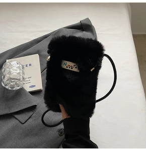 Détail d'un sac bandoulière en fausse fourrure noire avec étiquette Nakalin sur blazer
