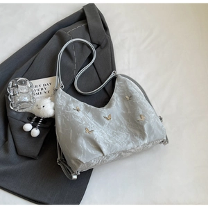 Detailed texture of grey pleated handbag with silver butterfly charms and cloud pendant
