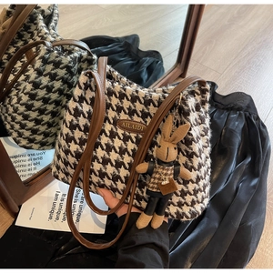 Detail of retro houndstooth tote bag with a leather handle and a cute rabbit charm