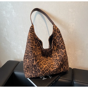 Détail du sac cabas imprimé léopard avec bandoulière en cuir brun et texture toile