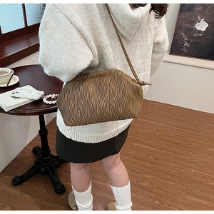 Detailansicht der braunen Falten-Cloud-Tasche am Modell in gemütlicher Café-Atmosphäre
