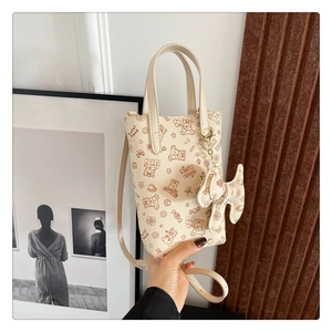 Détail du petit sac à téléphone crème avec imprimé ours et breloque nœud élégante