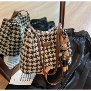 Detail of houndstooth tote bag with leather straps and cute bunny doll charm attachment