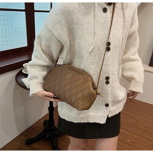 Braune gefaltete Umhängetasche kombiniert mit einem weißen Pullover im Innenbereich