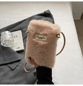 Détail du sac bandoulière en fausse fourrure rose avec étiquette et ferrures dorées