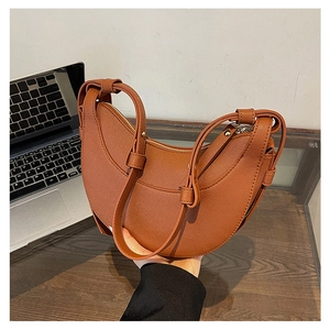 Dettaglio di una borsa a mezzaluna marrone con trama litchi e hardware color oro