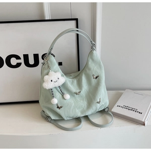 Detail of light green crescent shoulder bag with silver butterflies and cloud charm