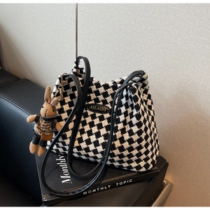 Detail of black and white houndstooth tote bag with brown rabbit plush charm and logo