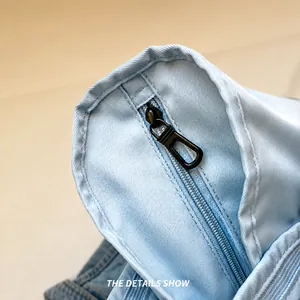 Detailed macro shot of a smooth black metal zipper on a light blue travel bag
