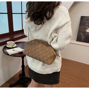 Detail der braunen Falten-Hobo-Tasche mit Wellentextur und Knotengurt in Lifestyle-Szene