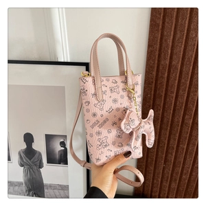 Détail d'un petit sac à bandoulière rose avec motifs d'ours et charm chien décoratif