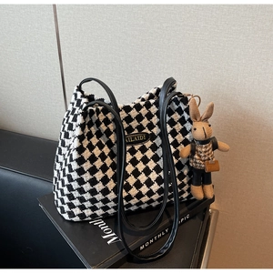 Detail of houndstooth tote bag with metal logo and cute rabbit doll charm accessory