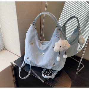 Detail of light blue wrinkled bag with silver butterfly clips and cloud charm