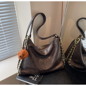 Close-up of vintage brown leather hobo bag with M-logo embossing and teddy bear charm