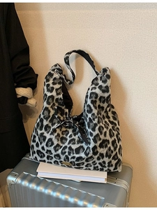 Modische Schultertasche mit Leopardenmuster und Schleife auf silbernem Koffer