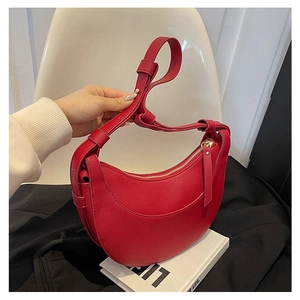 Dettaglio della borsa a mezzaluna in pelle rossa con tracolla regolabile e finiture in oro