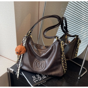 Detail of dark brown hobo shoulder bag with M-logo embossing and plush puppy charm
