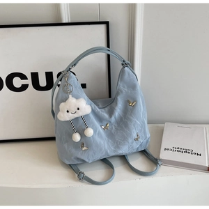 Detail view of light blue nylon bag with metal butterflies and cloud charm accessory