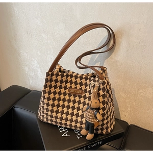 Detail of woven lattice tote bag with leather logo patch and cute rabbit charm