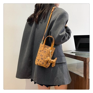 Détail du petit sac bandoulière marron avec imprimés ours et pendentif en forme de chien
