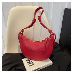 Dettaglio borsa a mezzaluna in pelle rossa scura con cerniera dorata e tracolla regolabile