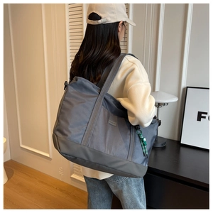 Close-up of grey large capacity tote bag with woven charm and durable nylon texture