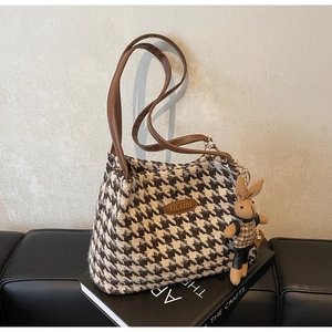 Detail of houndstooth tote bag with golden logo plaque and cute rabbit plush charm