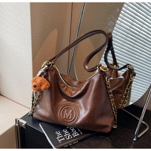 Detail of vintage brown leather hobo bag with embossed M logo and plush bear charm