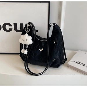 Detail of black wrinkled hobo bag featuring silver butterfly charm and plush cloud pendant