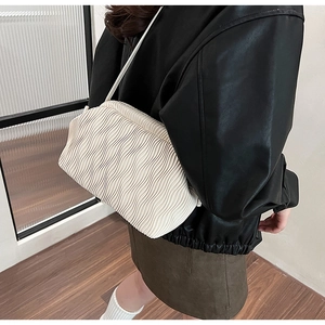 Detailansicht der cremefarbenen Falten-Schultertasche mit Wellenstruktur am Modell
