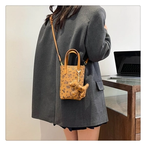 Vue détaillée du mini sac bandoulière marron à motif ours et breloque chien sur modèle