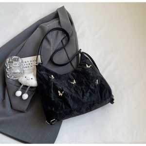 Detail of black pleated shoulder bag with silver butterfly and white cloud charm