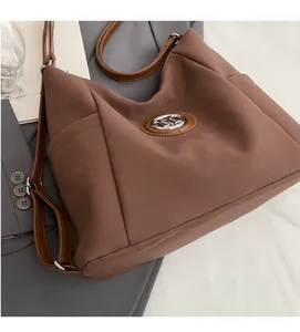 Close-up of the vintage brown suede bag featuring a metallic M logo and leather strap