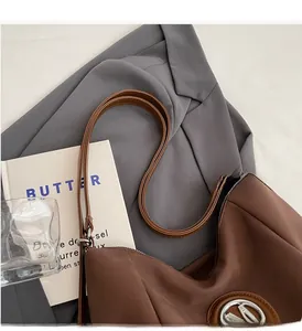 Close-up of dark brown nylon shoulder bag featuring silver metal logo and leather straps