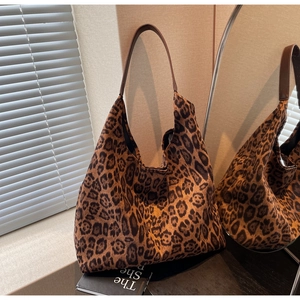 Gros plan d'un sac hobo léopard avec bandoulière en cuir brun via un reflet de miroir