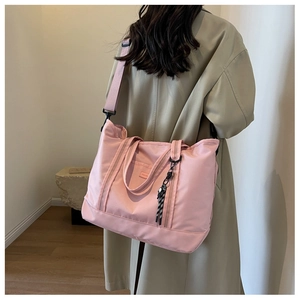 Side view of a large pink travel tote with wide shoulder strap worn by a model