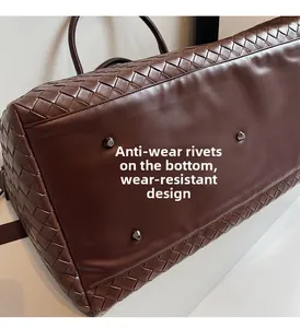 Detail of woven leather travel bag base with four protective metal feet for anti-wear