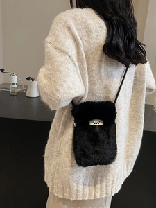 Petit sac bandoulière en peluche noire pour téléphone porté avec un pull d'hiver