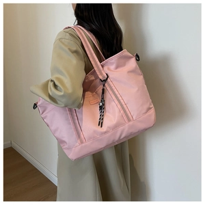 Close-up of pink large capacity travel tote bag with woven label and side hook detail