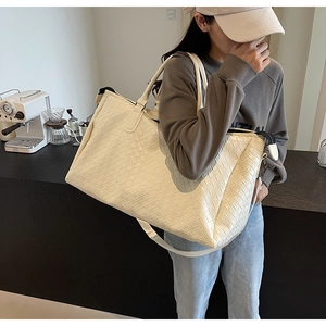 Detail of cream woven leather travel tote bag showing texture and adjustable strap