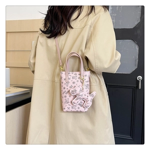 Détail de la pochette téléphone rose avec motifs de dessin animé et breloque