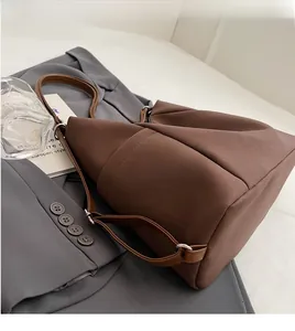 Close-up of adjustable silver buckle and smooth strap on a dark brown tote bag