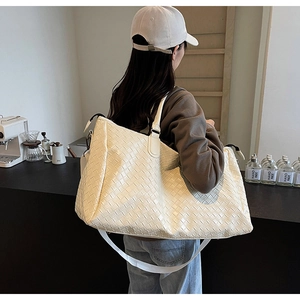 Detailed side view of the cream woven tote bag with adjustable shoulder strap and large grid