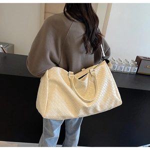 Close-up of cream woven travel tote with wide leather texture and shoulder strap