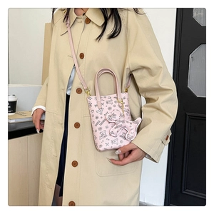 Mini sac bandoulière rose avec motif ours et breloque chien sur un manteau beige