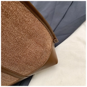 Detailed macro view of woven brown fabric and premium leather edge stitching on tote bag