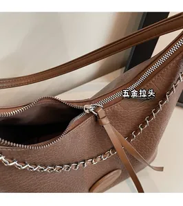 Close-up of smooth silver metal zipper and brown leather pull on vintage dumpling bag