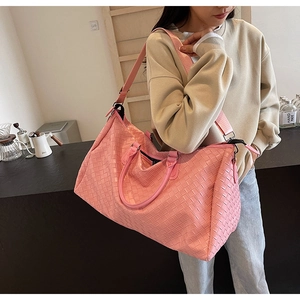 Close-up of pink woven leather texture and adjustable shoulder strap on travel bag